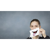 Pretty young girl holding white card with drawn smile showing tongue