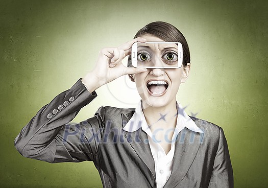 Beautiful young woman holding mobile phone against her eyes Beautiful young woman holding mobile phone against her eyes