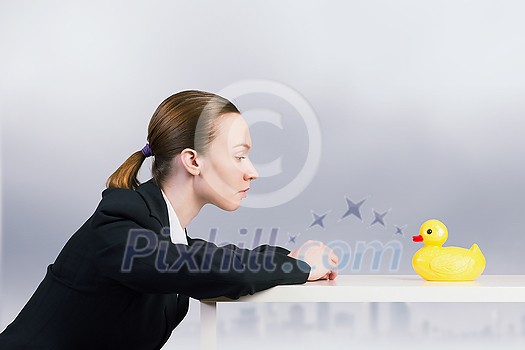 Young businesswoman and yellow rubber duck toy on table Young businesswoman and yellow rubber duck toy on table