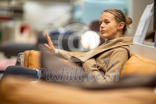 Pretty, young woman choosing the right furniture for her apartment in a modern home furnishings store (color toned image; shallow DOF) Pretty, young woman choosing the right furniture for her apartment in a modern home furnishings store (color toned image; shallow DOF)