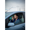 Handsome young man calling on his cellphone while at the wheel of his car, smiling