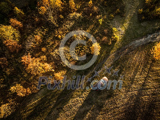 Aerial view of an off-road car amid splendid, colorful autumnal landscape Aerial view of an off-road car amid splendid, colorful autumnal landscape