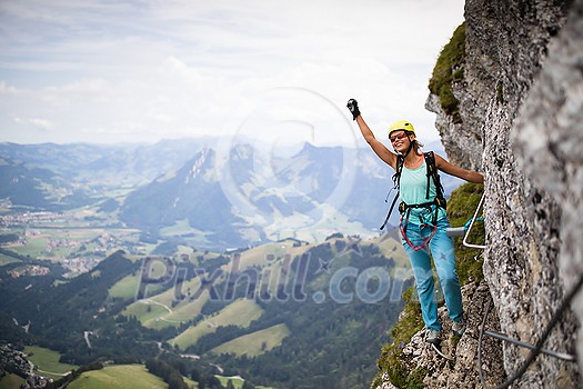 Pretty, female climber on a via ferrata - climbing on a rock in Swiss Alps Pretty, female climber on a via ferrata - climbing on a rock in Swiss Alps