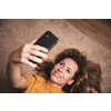 Happy mid-aged woman taking selfie with her smart phone at home