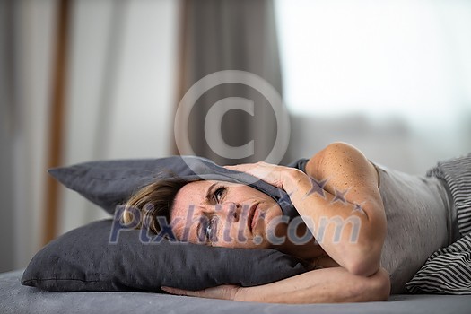 Sleepless lady covering ears with pillow. Noisy neighbors, tinnitus, insomnia or stress concept. Tired woman can't sleep. Awake in bed after coming home from her shift, work. Sleepless lady covering ears with pillow. Noisy neighbors, tinnitus, insomnia or stress concept. Tired woman can't sleep. Awake in bed after coming home from her shift, work.