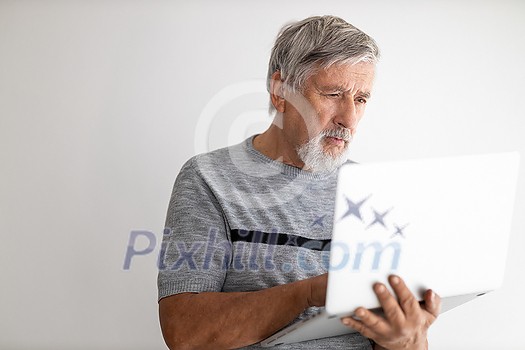 Senior man using a laptop computer at home, struggling with techology a bit, shopping online during COVID confinement/lockdown/quarantine Senior man using a laptop computer at home, struggling with techology a bit, shopping online during COVID confinement/lockdown/quarantine