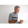 Senior man using a laptop computer at home, struggling with techology a bit, shopping online during COVID confinement/lockdown/quarantine