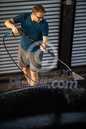 Young man washing his beloved car carefully in a manual car wash to prevent any damage and detail it properly Young man washing his beloved car carefully in a manual car wash to prevent any damage and detail it properly