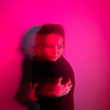Depressed young woman in front of a wall lit by red light, lonely, anxious (color toned image)