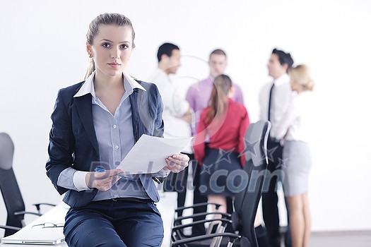 Successful business woman standing with her staff in background at modern bright office Successful business woman standing with her staff in background at modern bright office