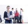 Successful business woman standing with her staff in background at modern bright office