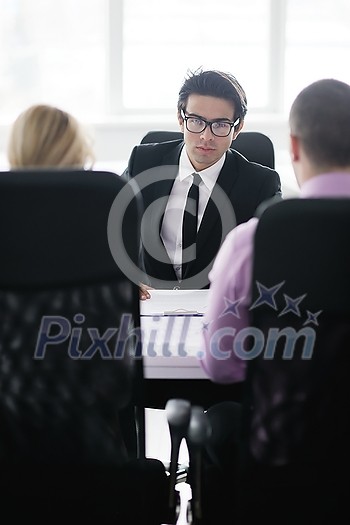 Group of young business people sitting in board room during meeting and discussing with paperwork Group of young business people sitting in board room during meeting and discussing with paperwork