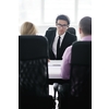 Group of young business people sitting in board room during meeting and discussing with paperwork