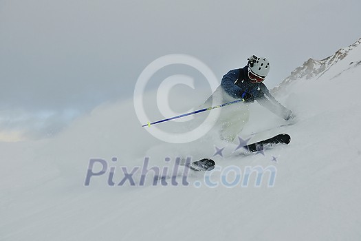 skier skiing downhill on fresh powder snow with sun and mountains in background skier skiing downhill on fresh powder snow with sun and mountains in background