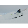 skier skiing downhill on fresh powder snow  with sun and mountains in background