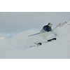 skier skiing downhill on fresh powder snow  with sun and mountains in background