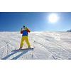 skier skiing downhill on fresh powder snow  with sun and mountains in background