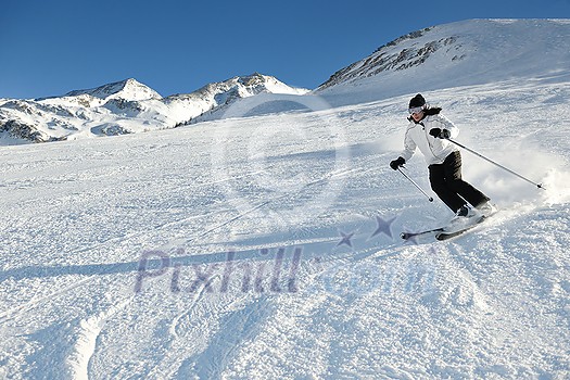 skier skiing downhill on fresh powder snow with sun and mountains in background skier skiing downhill on fresh powder snow with sun and mountains in background