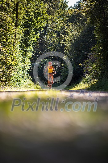 Pretty, young woman biking on a mountain bike enjoying healthy active lifestyle outdoors in summer (shallow DOF) Pretty, young woman biking on a mountain bike enjoying healthy active lifestyle outdoors in summer (shallow DOF)