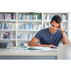 Students in a library - handsome student reading a book for his class in a bright modern library