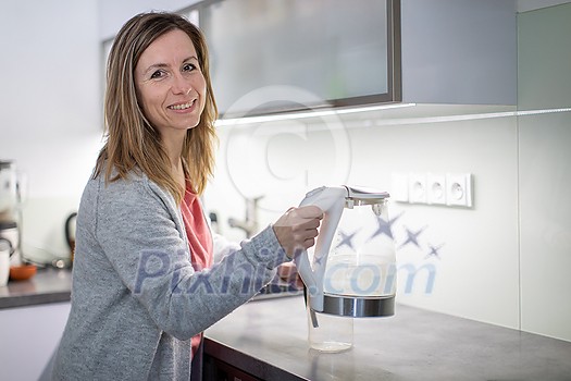 Pretty, young woman in her modern bright kitchen - making tea, healthy eating concept, household lifestyle concept Pretty, young woman in her modern bright kitchen - making tea, healthy eating concept, household lifestyle concept