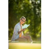 Young Beautiful Suntanned Woman wearing sunglasses relaxing next to a Swimming Pool  on a lovely Summer Day  - Reading a book