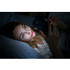 Young woman in bed holding a phone, tired and exhausted, blue light straining her eyes, messing up her circadian rhytm