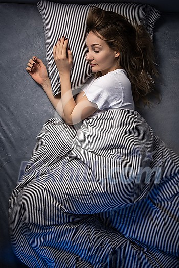 Pretty, young woman sleeping in her bed late in the morning on a weekend - compensating for the lack of sleep Pretty, young woman sleeping in her bed late in the morning on a weekend - compensating for the lack of sleep
