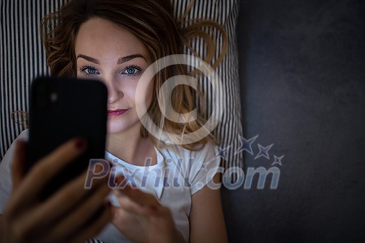 Young woman in bed holding a phone, tired and exhausted, blue light straining her eyes, messing up her circadian rhytm Young woman in bed holding a phone, tired and exhausted, blue light straining her eyes, messing up her circadian rhytm