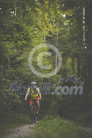 Young man with his mountain bike going for a ride past the city limits in a lovely forest, getting the daily cardio dose Young man with his mountain bike going for a ride past the city limits in a lovely forest, getting the daily cardio dose
