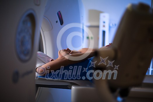 Pretty, young woman goiing through a Computerized Axial Tomography (CAT) Scan medical test/examination in a modern hospital (color toned image; shallow DOF) Pretty, young woman goiing through a Computerized Axial Tomography (CAT) Scan medical test/examination in a modern hospital (color toned image; shallow DOF)