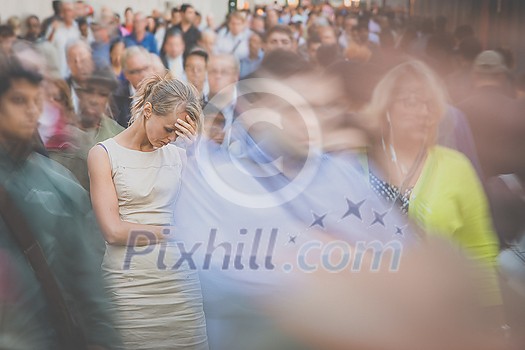 Crowd of people walking on city street - motion blurred image with unrecognizable faces - Young woman standing still, feeling down, depressed Crowd of people walking on city street - motion blurred image with unrecognizable faces - Young woman standing still, feeling down, depressed