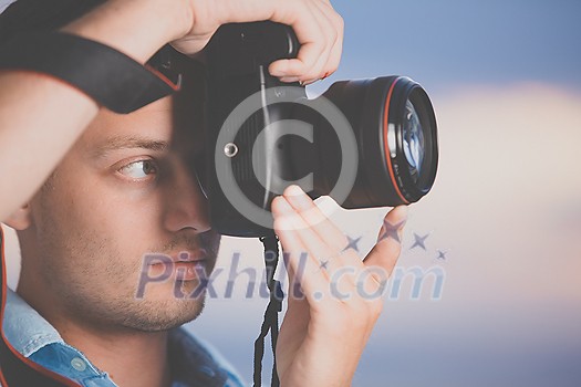 Handsome young photographer using his modern DSLR outdoors, against lovely sky backdrop (color toned image;shallow DOF) Handsome young photographer using his modern DSLR outdoors, against lovely sky backdrop (color toned image;shallow DOF)