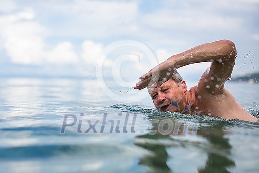 Senior man swimming in the Sea/Ocean - enjoying active retirement, having fun, taking care of himself, staying fit Senior man swimming in the Sea/Ocean - enjoying active retirement, having fun, taking care of himself, staying fit