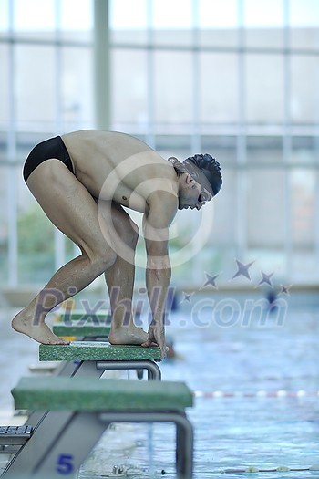 young swimmer on swim start at swimming pool ready for jump race and win young swimmer on swim start at swimming pool ready for jump race and win