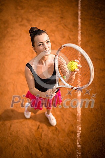 Top view of attractive young woman tennis player serving on a clay tennis court. Interesting POV shot - sporty girl during tennis training in the club Top view of attractive young woman tennis player serving on a clay tennis court. Interesting POV shot - sporty girl during tennis training in the club