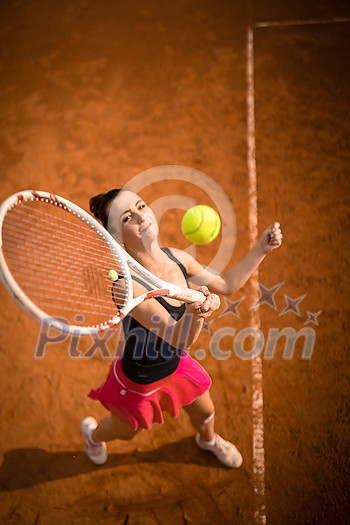 Top view of attractive young woman tennis player serving on a clay tennis court. Interesting POV shot - sporty girl during tennis training in the club Top view of attractive young woman tennis player serving on a clay tennis court. Interesting POV shot - sporty girl during tennis training in the club