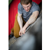 A rock climber climbing on a boulder rock outdoors. Group of friends involved in sports outside.