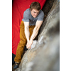 A rock climber climbing on a boulder rock outdoors. Group of friends involved in sports outside.