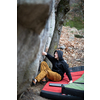 A rock climber climbing on a boulder rock outdoors. Group of friends involved in sports outside.