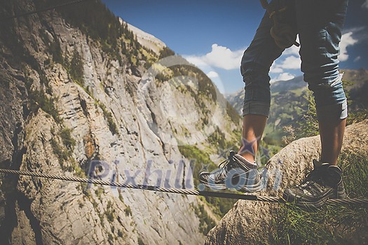 Man on a via ferrata, walking on an iron rope. Kandersteg - amazing vacation destination in the Swiss Alps, Switzerland Man on a via ferrata, walking on an iron rope. Kandersteg - amazing vacation destination in the Swiss Alps, Switzerland