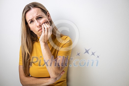 Mid-aged woman touching her cheek/mouth with painful expression because of toothache/dental issue