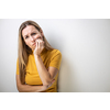 Mid-aged woman touching her cheek/mouth with painful expression because of toothache/dental issue