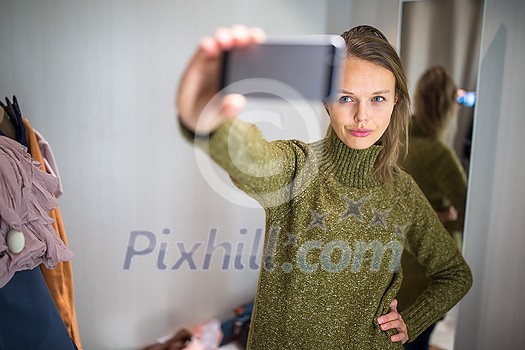 Young woman shopping in a fashion store, trying on some clothes she likes (color toned image; shallow DOF) Young woman shopping in a fashion store, trying on some clothes she likes (color toned image; shallow DOF)