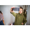 Young woman shopping in a fashion store, trying on some clothes she likes (color toned image; shallow DOF)