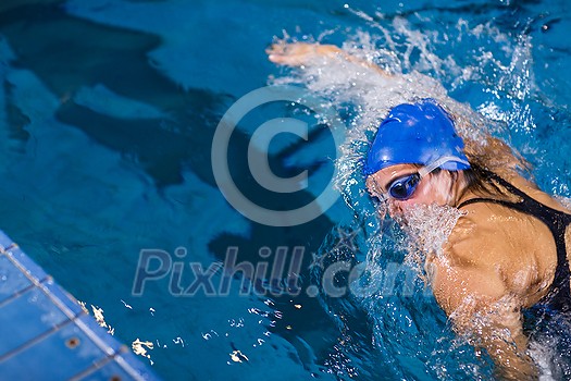 Female swimmer in an indoor swimming pool - doing crawl (shallow DOF) Female swimmer in an indoor swimming pool - doing crawl (shallow DOF)