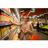 Pretty, young woman shopping for her favorite fruit juice/smoothie at a grocery store