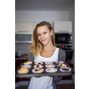 Pretty, young woman baking gluten free cupkes - taking them out of the oven, being pleased with the result