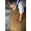 DIY, repair, building and home concept - close up of male hands lying parquet floor board/laminate flooring (shallow DOF; color toned image)