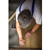 DIY, repair, building and home concept - close up of male hands lying parquet floor board/laminate flooring (shallow DOF; color toned image)